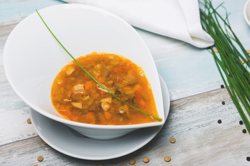 lentil soup with chorizo and vegetables on a wooden table