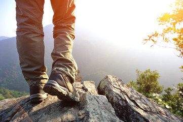 woman hiker legs stand on mountain peak rock 