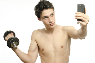 Skinny man taking selfie with phone while training biceps