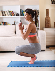 Young woman doing yoga in her living room.