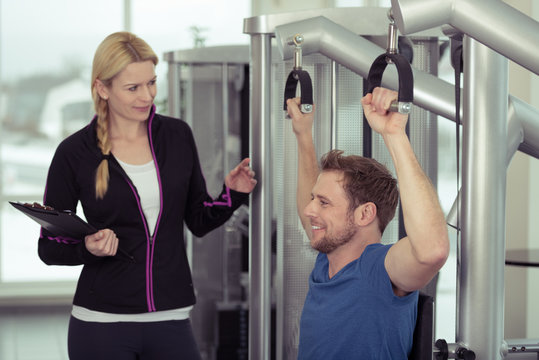 trainerin berät einen mann am fitness-gerät