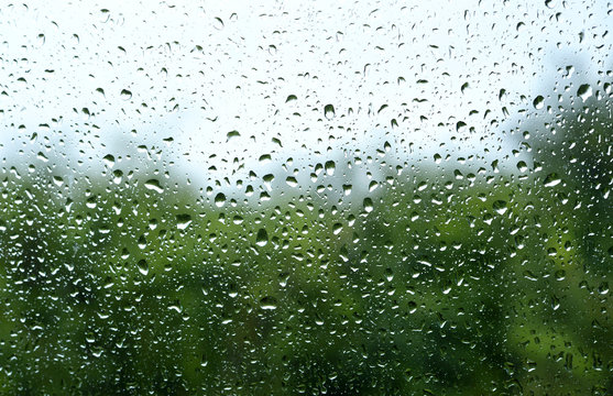 Rain drops on a window with a blurred green landscape