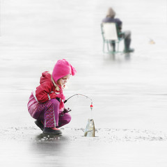 Little child fishing on a frozen lake in winter.