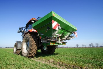 Ackerbau, Traktor mit Düngerstreuer bei der Frühjahrsdüngung