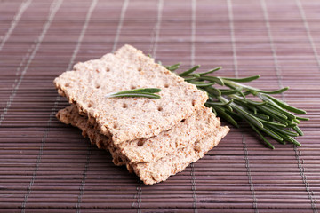Crispbread with sprigs of rosemary on bamboo mat background