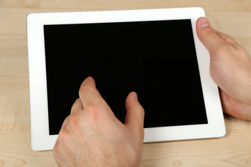 Hands using tablet PC on wooden table background