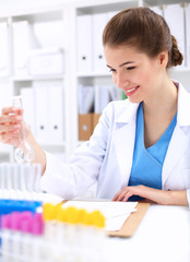 Woman researcher is surrounded by medical vials and flasks,