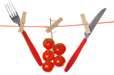 Fork, knife and ripe red tomatoes hanging from clothesline