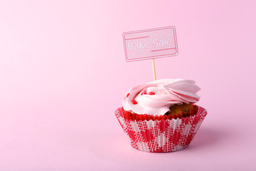 Delicious cupcake with inscription on color background