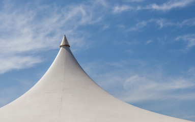 Looking up at the top of white tent against beautiful blue sky.