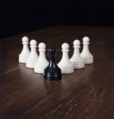 Black pawn in focus on a background white pawns.