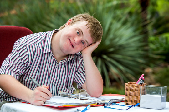 Handicapped Boy Resting On Hand At Desk.