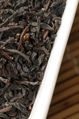 close up of black tea leaves in white bowl