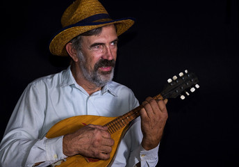 Portrait (low key) of an old country man with mandolin