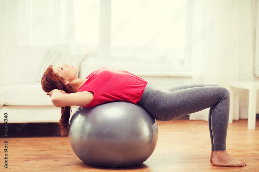 Wall mural smiling redhead girl exercising with fitness ball