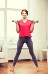 Fototapeta na wymiar smiling teenage girl exercising with dumbbells