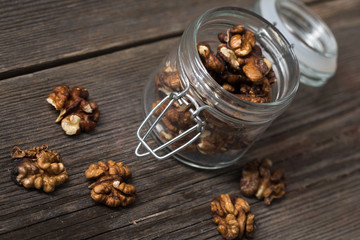 Walnuts in glass jar on wooden background