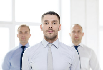 Fototapeta premium serious businessman in office with team on back