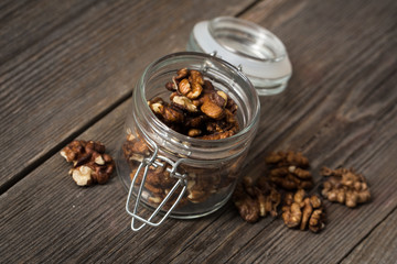 Walnuts in glass jar on wooden background