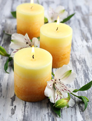 Beautiful candles with flowers on wooden background