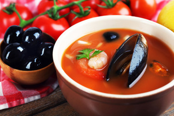 Tasty soup with shrimps, mussels, tomatoes and black olives in