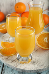 Glass of orange juice with slices on color wooden background