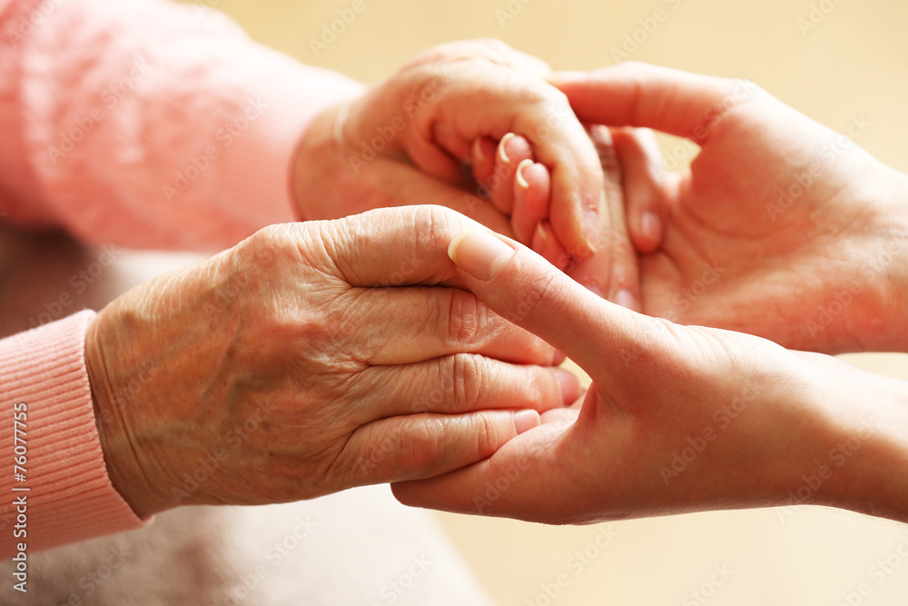 Canvas Prints Old and young holding hands on light background