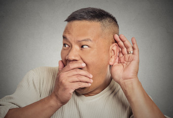 Shocked man hand to ear listening eavesdropping grey background 