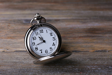 Silver pocket clock on wooden background