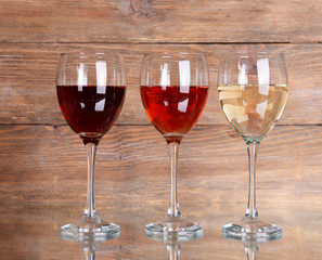 Different glasses of wine on table on wooden background