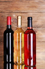 Different bottles of wine on table on wooden background