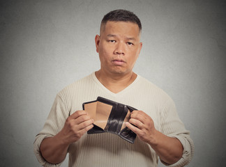 Sad man holding empty wallet isolated on grey background 
