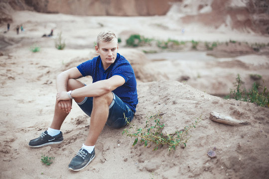Young man sitting on the sand alone