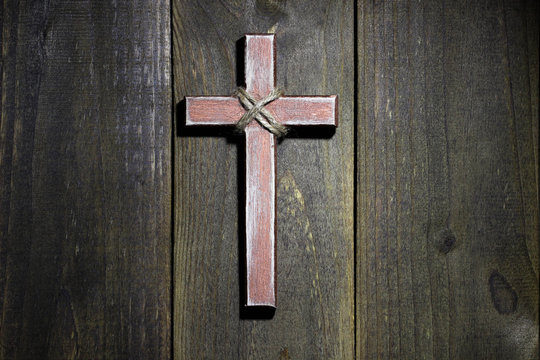 Wooden cross hanging on rustic wood background