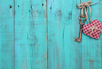 Key and heart hanging on teal blue wood background
