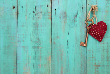 Red heart and key hanging on antique wood background