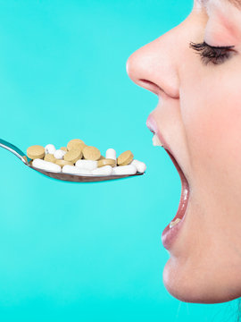 Young Woman Eating Pills On A Spoon