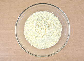 Cornflour in a glass bowl on wooden background.