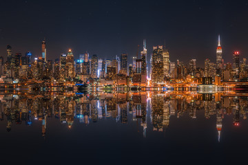 Lower Manhattan skyline at night reflected in water - obrazy, fototapety, plakaty