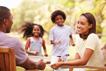 Parents Relaxing Whilst Children Play In Garden