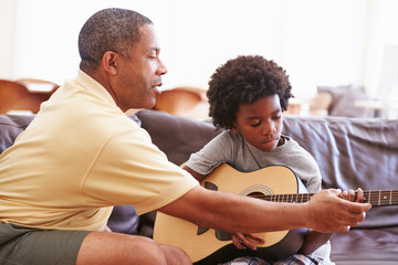 Grandfather Teaching Grandson To Play Guitar