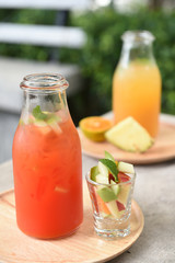 different bottles of juice with fruits on wooden table