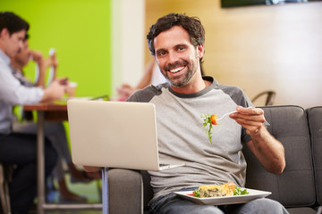 Man Sitting On Sofa And Eating Lunch In Design Studio