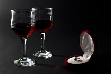 Golden Ring in Jewelry Box and Glass Cups Filled with Red Wine