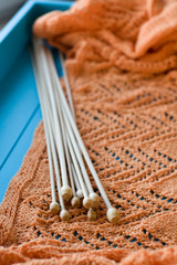 Many wooden spokes lie on an orange knitted plaid