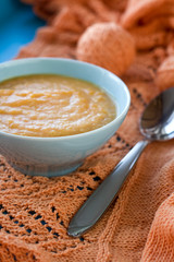 Dietary pumpkin porridge in the blue plate on an orange knitted