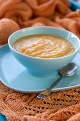 Dietary pumpkin porridge in the blue plate on an orange knitted
