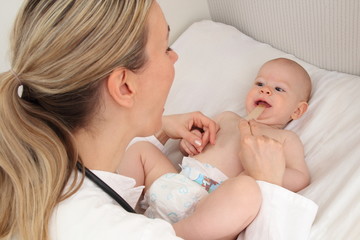Kinderärztin untersucht Baby mit Mundspatel