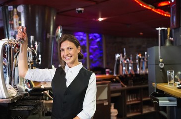 Happy barmaid pulling a pint of beer