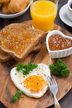 Fried eggs in the form of heart on wooden board, top view